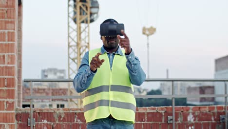 African-American-man-architect-or-foreman-in-VR-glasses-standing-on-the-roof-at-the-building-site-and-having-headset-as-watching-virtual-tour-of-future-architecture.-Outdoors.-New-modern-technologies.